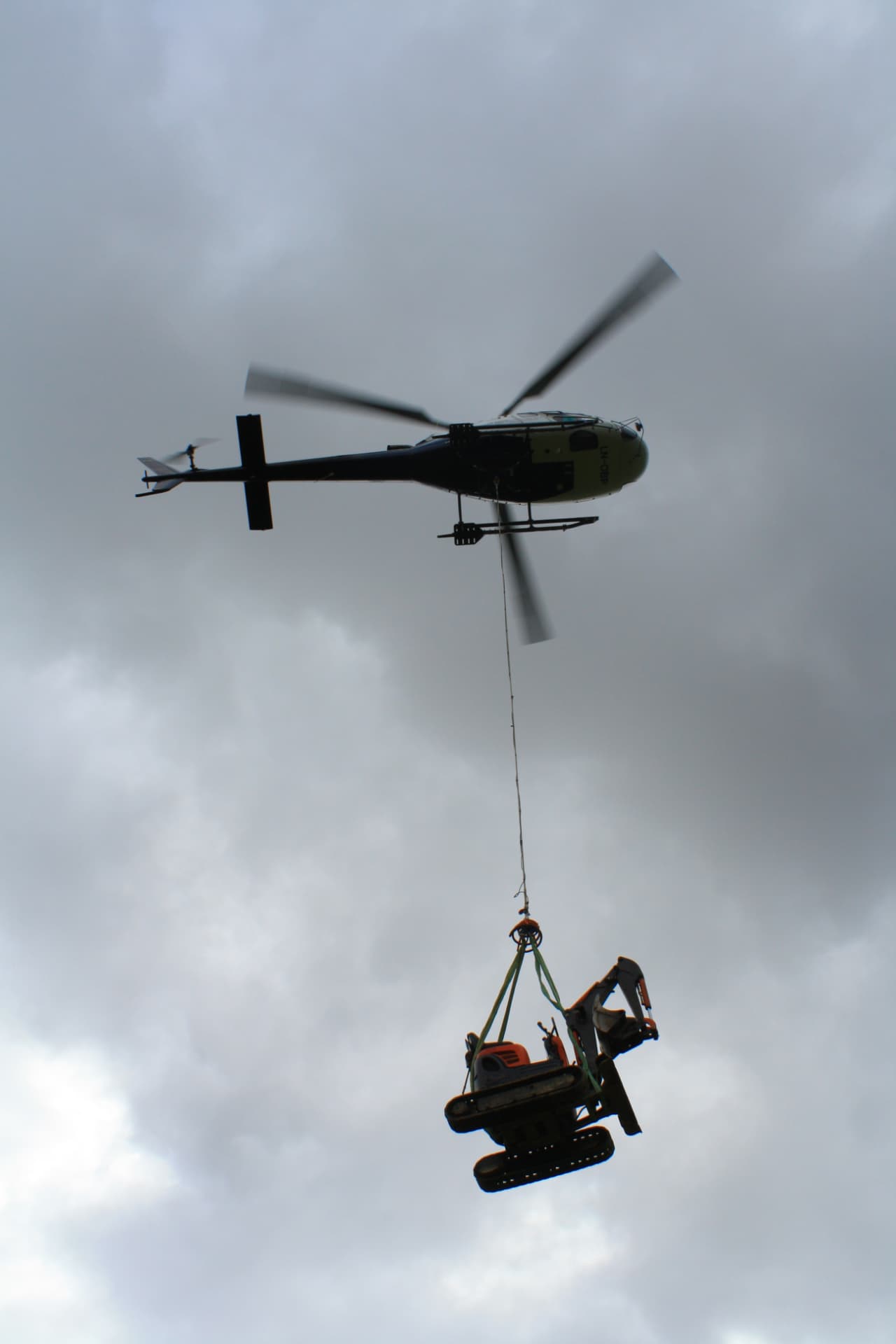Helikopter løfter en gravemaskin i lasteline